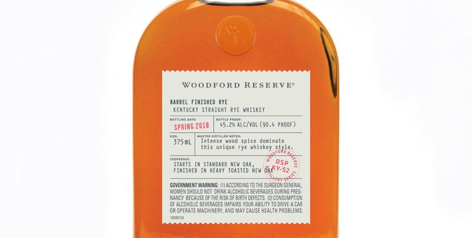 Woodford bottle with light color bourbon and white background
