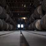dark image of bourbon barrels stacked in a barn on both sides