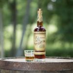kentucky owl bottle with glass of bourbon on a barrel