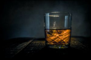 Whiskey: glass on a dar wooden bar with a dark background