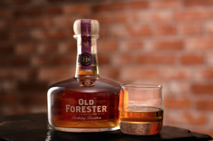 Old Forester: bottle of bourbon and a glass with bourbon and a brick wall in the background