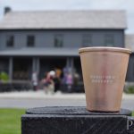 bourbon: a rose gold cup that says Woodford Reserve and a blurry building in the background